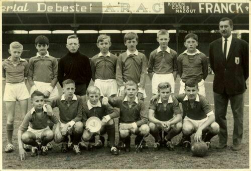 Foto van een jeugdelftal van de ARAG uit 1965. De bestuurder rechts draagt een Buffalo op de borst. Een jeugdspeler op de onderste rij toont een schaal met de Buffalo van de atletiekafdeling. (Foto: Archief Robert De Grauwe/KAA Gent Foundation)